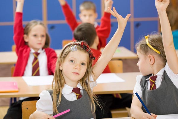 Primary school children with their hands raised